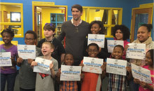 Room full of children receiving certificates from Michael Phelps.
