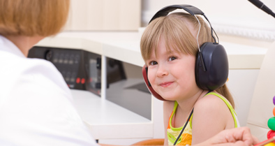 Smiling girl taking a hearing test for Central Auditory Processing Disorder (CAPD).